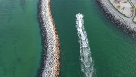 La-Cámara-De-Drones-Sigue-El-Jet-ski,-El-Deporte-Acuático-En-El-Paraíso,-El-Agua-Cristalina-Azul-verde-De-La-Costa-De-La-Playa-Mamzar-De-Dubai,-El-Mar-Arábigo,-La-Principal-Atracción-Turística,-Imágenes-De-4k