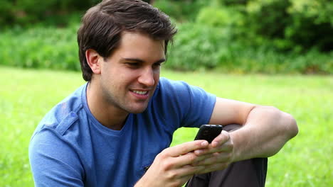 hombre sonriente escribiendo en su teléfono móvil