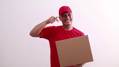 happy young asian courier man holding cardboard while pointing on it