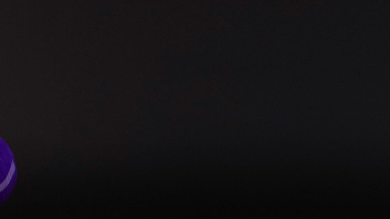 A purple tennis ball moves across a dark grid, showcasing dynamic motion and contrast.