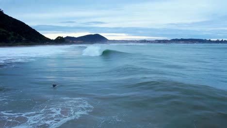 la ola baja se acerca y crece, pero permanece suave, el surfista la salta