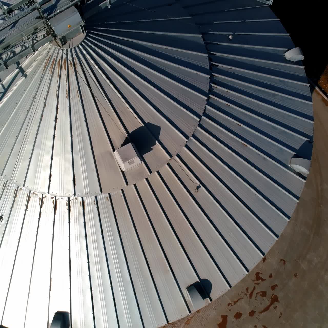 moderno granero a la luz del sol. elevador de granos. gran contenedor de plata para productos agrícolas. primer plano. vista desde arriba. cámara moviéndose en redondo.