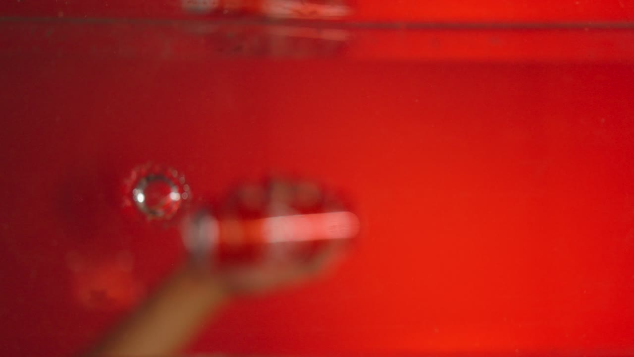 Hand goes into water and pulls out a cold cola can, red background and suitable for use for advertisements