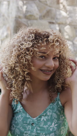 vertical video: biracial young woman standing outdoors, smiling broadly