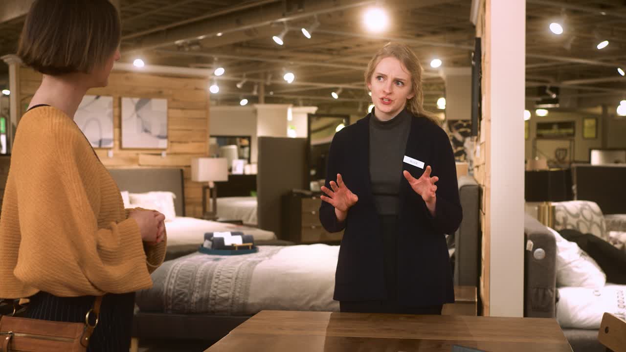Un addetto alle vendite pone domande a un cliente all'interno di un negozio di mobili
