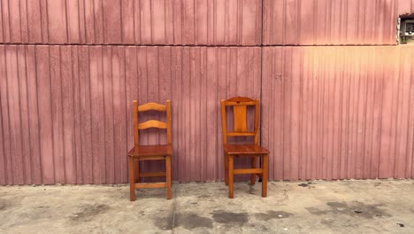 creatively filmed scene showcasing two wooden chairs arranged in front of a metal container, evoking a unique atmosphere and aesthetic allure