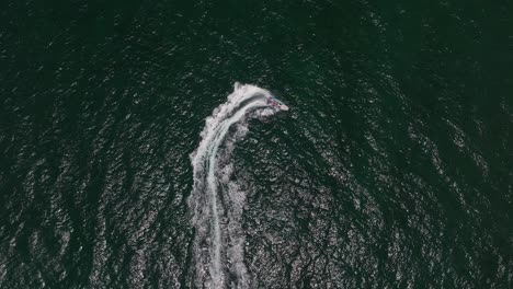 Extreme-jet-boat-roaring-across-the-sea-with-tourists,-Aerial-footage