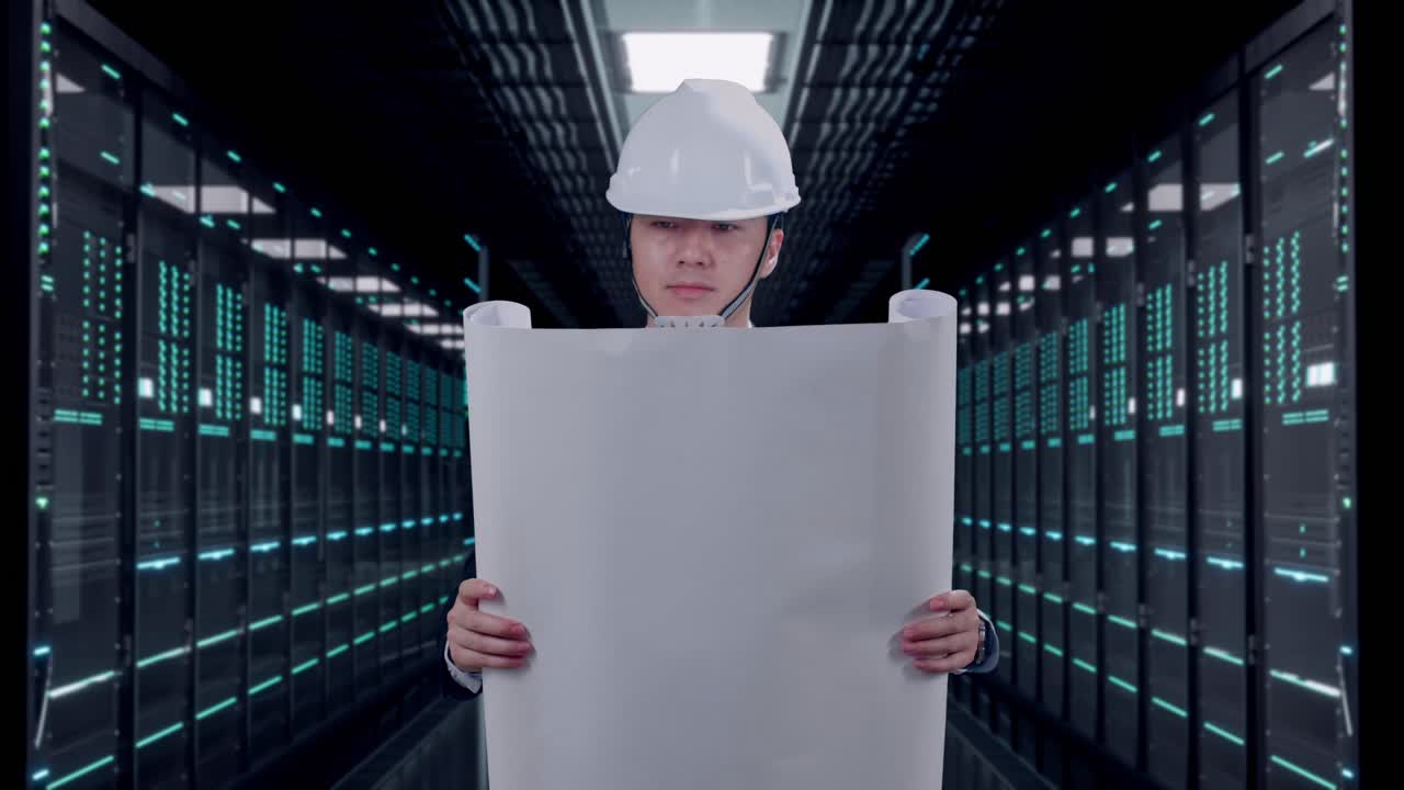 Front View of Asian Businessman Looking At Blueprint In His Hands While Walking in Server Room Data Center