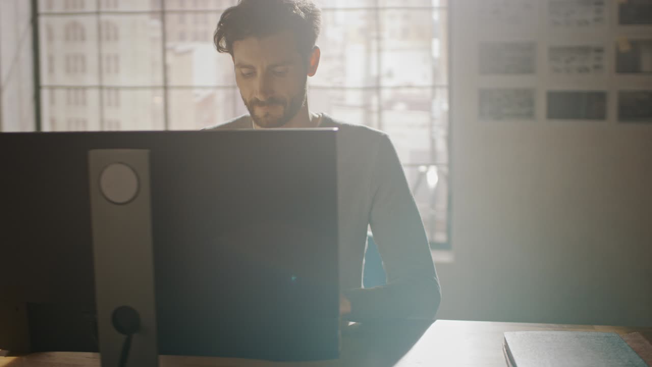 Creative Designer Sitting at His Desk in Office Studio Working on a Desktop Computer with Smartphone Software Development Application on Screen. Web, App Developer. 360 Degree Tracking Arc Shot