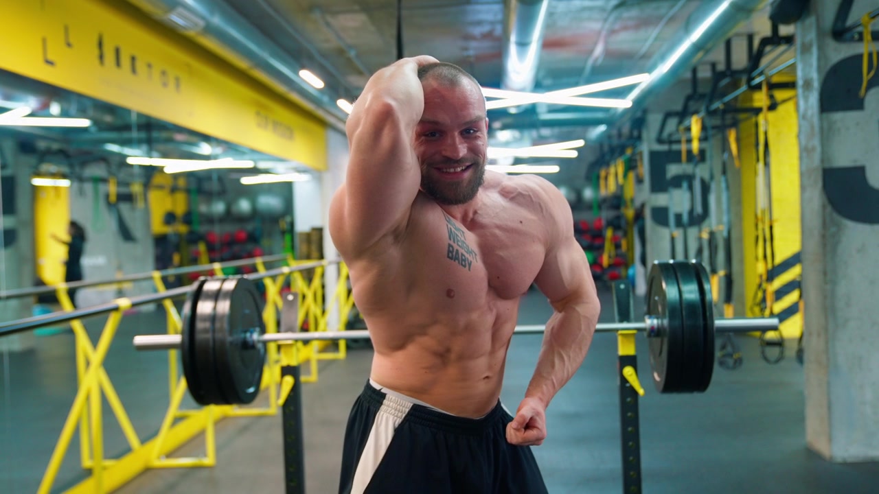 Bodybuilder muscoloso che posa e flette i muscoli in una palestra