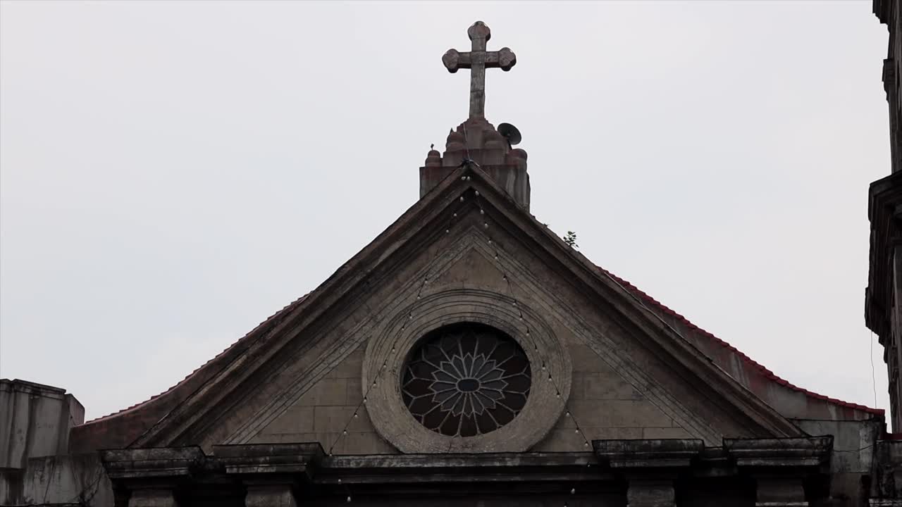 cruz en la parte superior de una iglesia en manila en las filipinas en un día nublado
