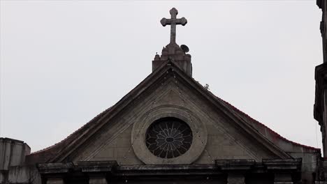 cross on top of a church in manila in the philippines on a cloudy day