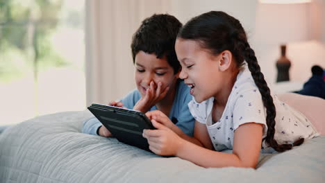niños viendo la tableta en la cama