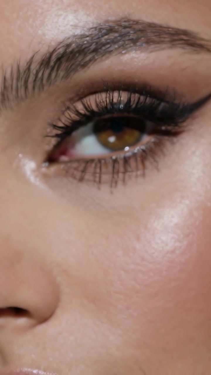 Vertical video: Pulling focus, camera revealing winged eyeliner and lip gloss on woman in studio