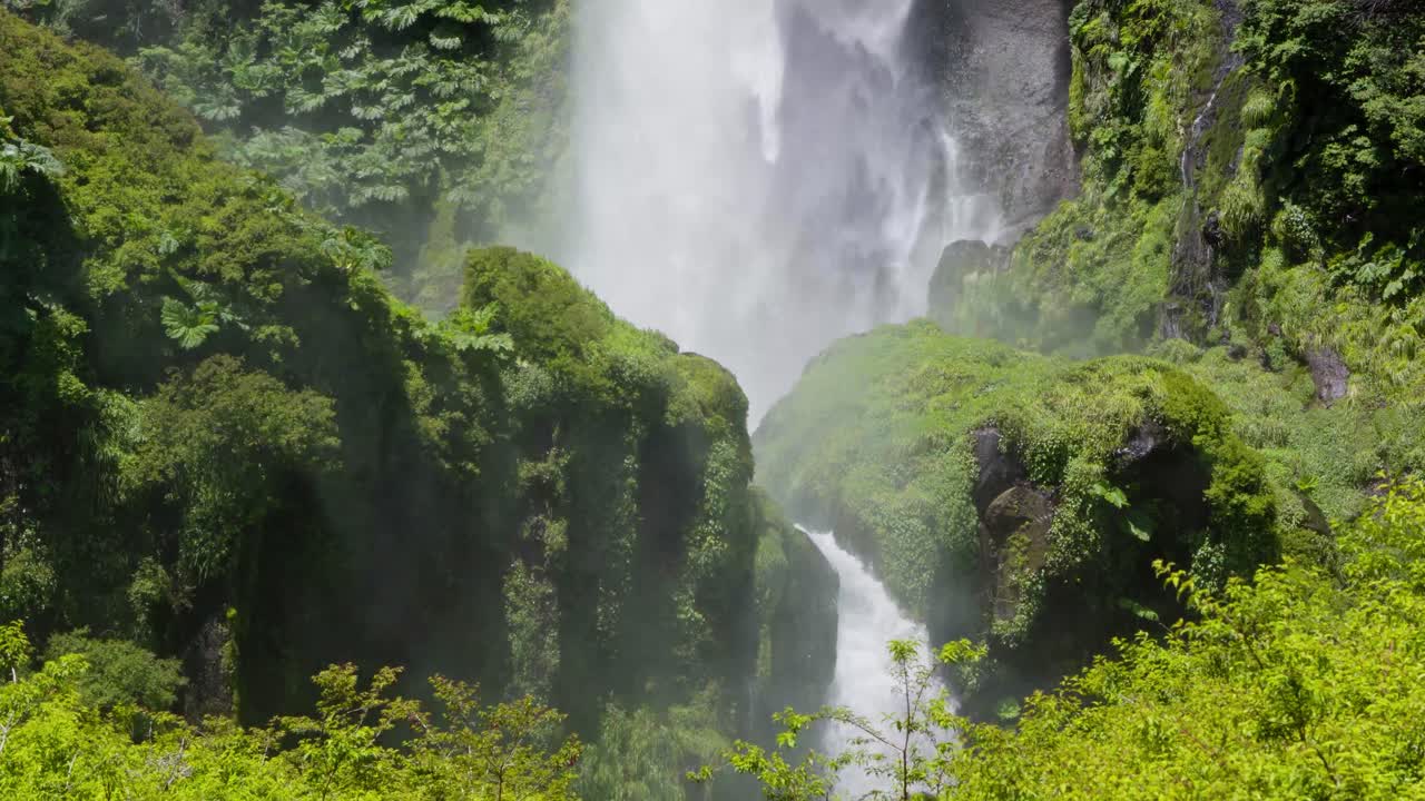 Close up of Salto El Leon waterfall falling down and spraying water in dense green rainforest near Pucon, Chile