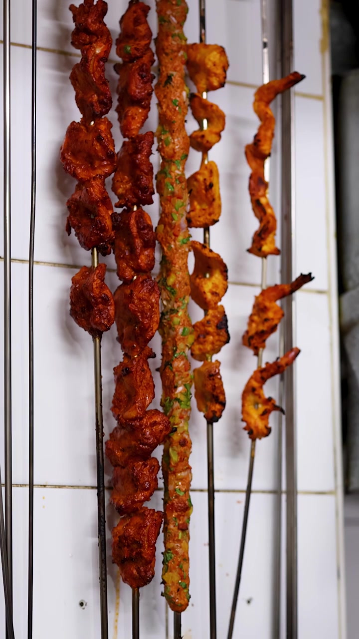 Valikoima intialaisia tandoori-kebabeja kypsymässä metallivartaissa