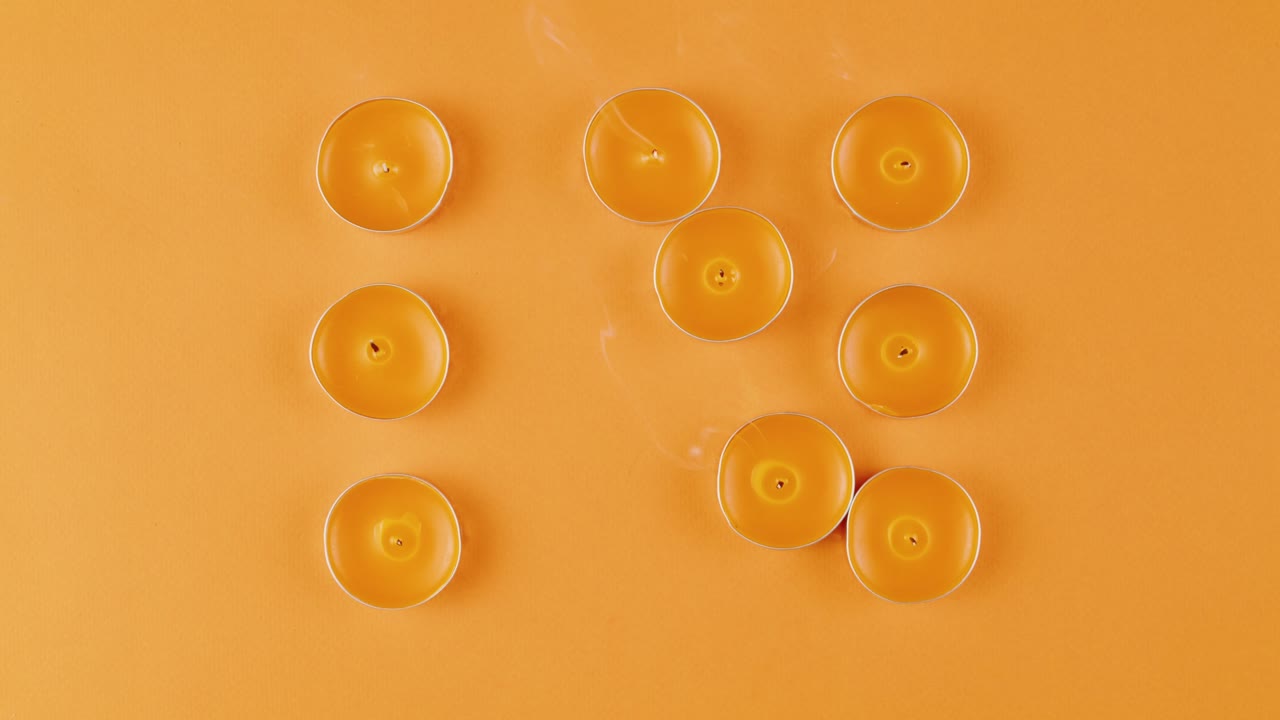 Arranged Tea Lights on Orange Background