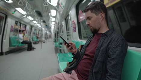 hombre usando un teléfono inteligente en un metro