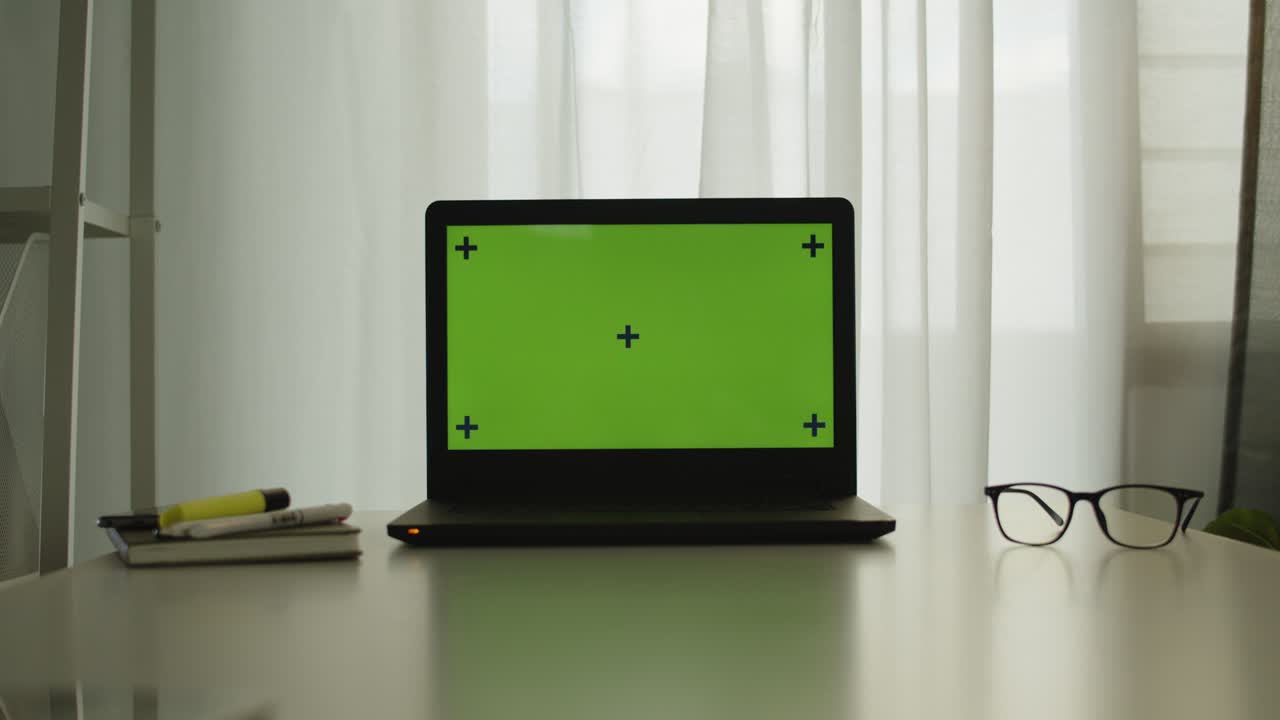 Shot of a laptop with chroma key green screen on a table in office room.