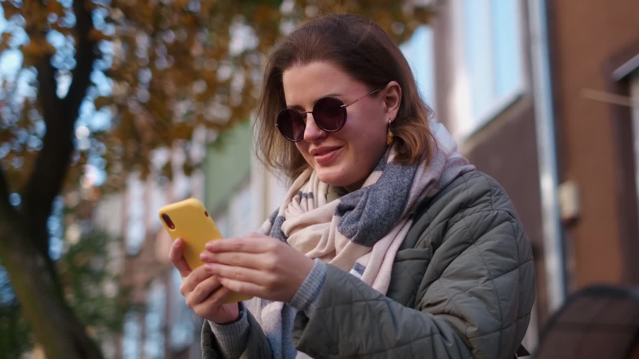 Woman using phone in autumn city