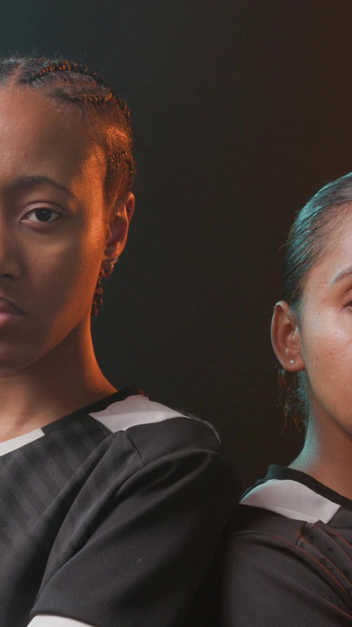 Vertical video: Camera zooming, team posing back-to-back in studio black jerseys, rim lighting