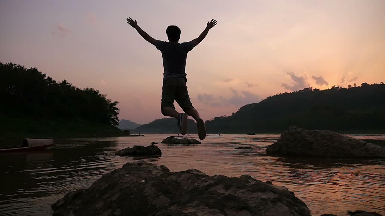 Man Jumping and Celebrating Sunset by the River
