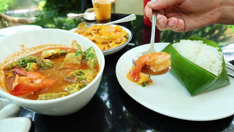 hand serving thai sour soup into plates