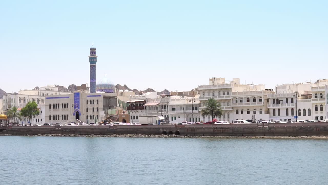 Veduta di una città costiera in Oman con architettura moderna di tipo mediorientale sullo sfondo e una moschea