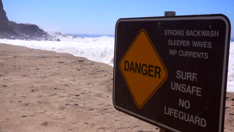 a sign along a california beach warns of dangerous surf and strong rip currents