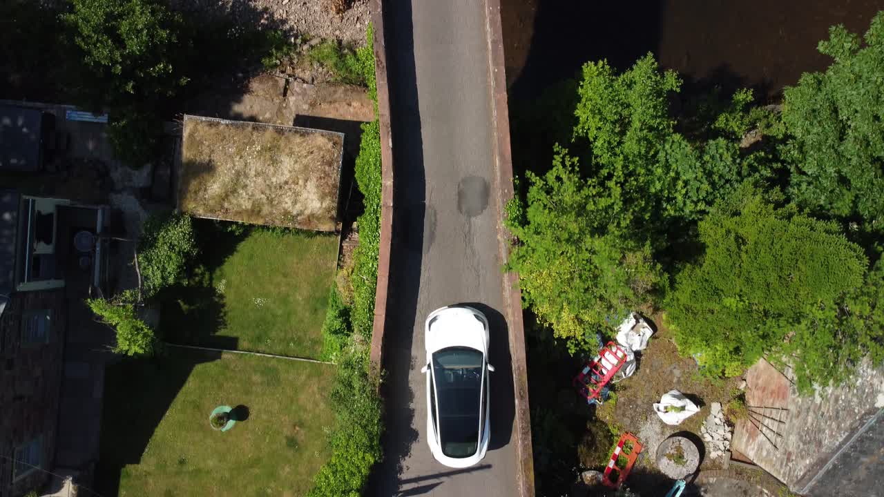 el coche blanco pasa por un puente estrecho con un vehículo negro que viene por el otro lado