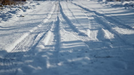 snowy road wheel marks sunny winter day close up. snow-covered rural roadway.