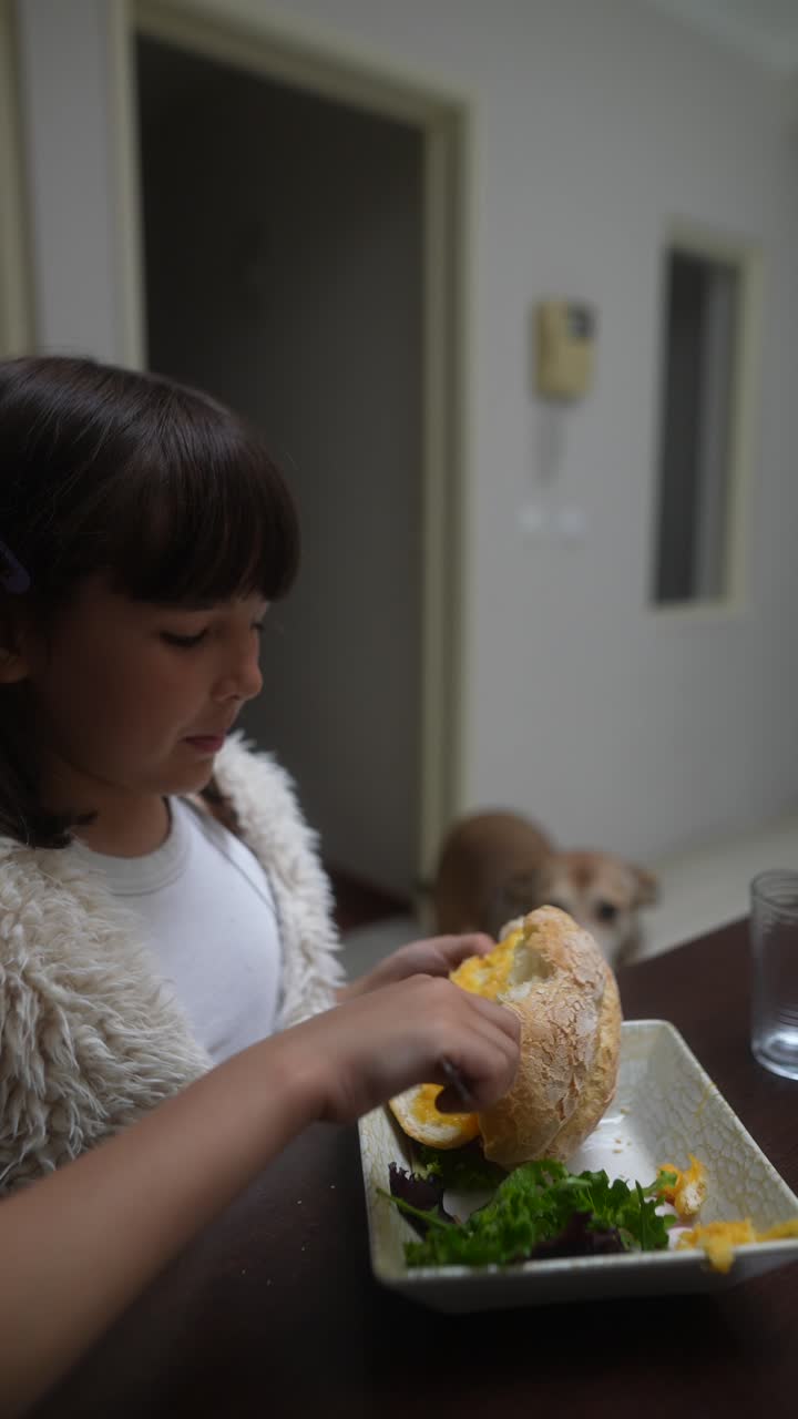 Ragazza che mangia un panino a tavola