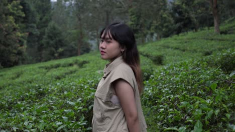 indonesian girl standing in tea plantation, facing sideways with a relaxed vibe