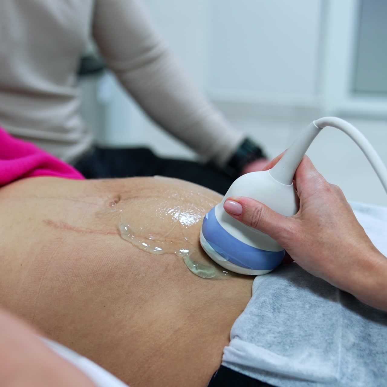 Doctor's hand moving the device by the belly of a woman. Ultrasound check up of pregnancy