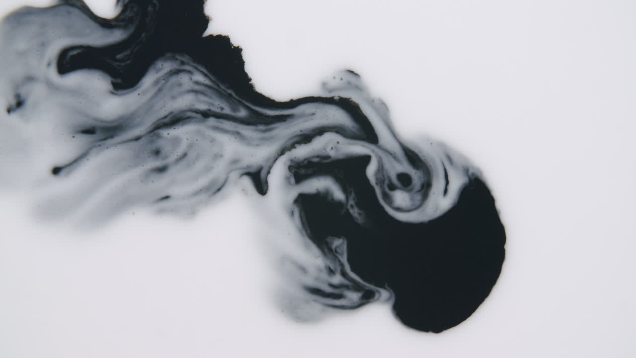 Dark black liquid dissolving slowly into a white liquid