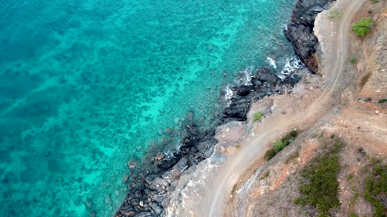 수정처럼 맑고 아름다운 청록색 바다 위로 떠오르는 파도, 바위 해안으로 밀려드는 파도, 거칠고 먼지가 자욱한 구불구불한 선로