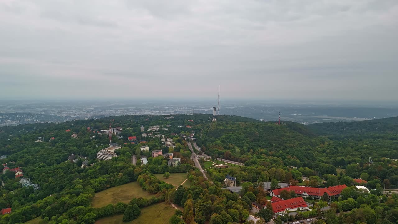 Aerial hyperlapse from Budapest, Normafa, flying toward the Széchenyi-hegyi transmission tower under a cloudy sky in Hungary