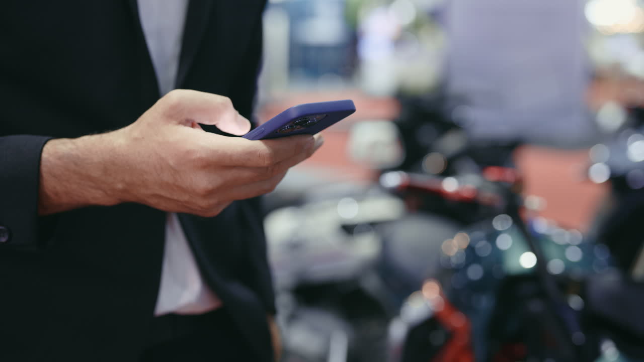 Businessman using smartphone at motorcycle exhibition