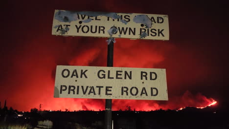 Street-sign,-Travel-this-road-at-your-own-risk,-Huge-Fairview-fire-blazes-at-Night,-California