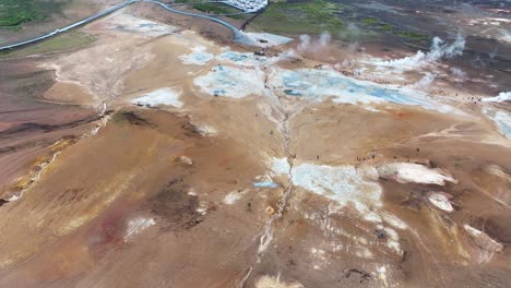 aerial view of geothermal area in landscape of iceland, geysir hot springs, vapors and people, drone shot