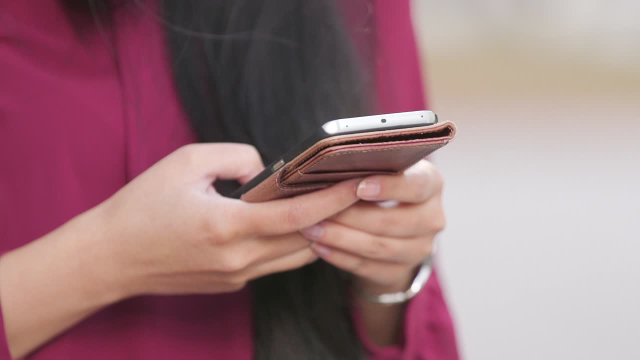 mujer con cabello largo y vestido rojo enviando mensajes de texto en su teléfono de cerca