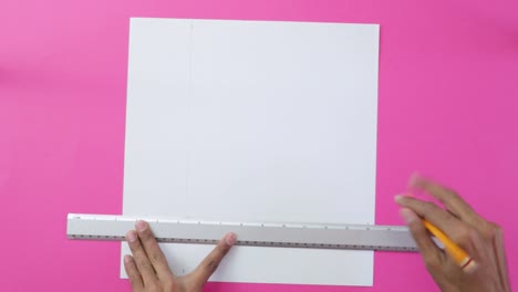 tracing straight lines on paper with pencil and ruler, pink background