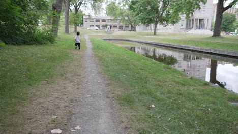 child running in outdoor garden. slow motion video of child running at outside home garden. kid running zig zag with a stick in his hand.