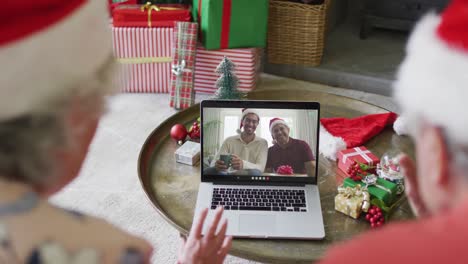 Senior-caucasian-couple-using-laptop-for-christmas-video-call-with-happy-family-on-screen