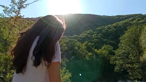 una mujer en un bosque admirando el sol.