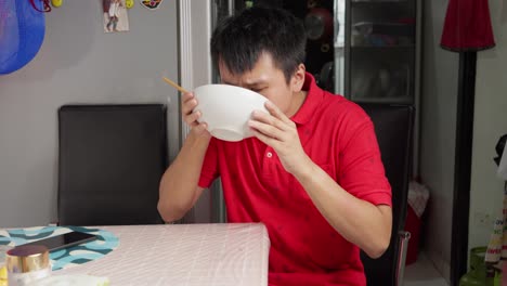 young chinese man eating bakmi wheat-based noodles at home