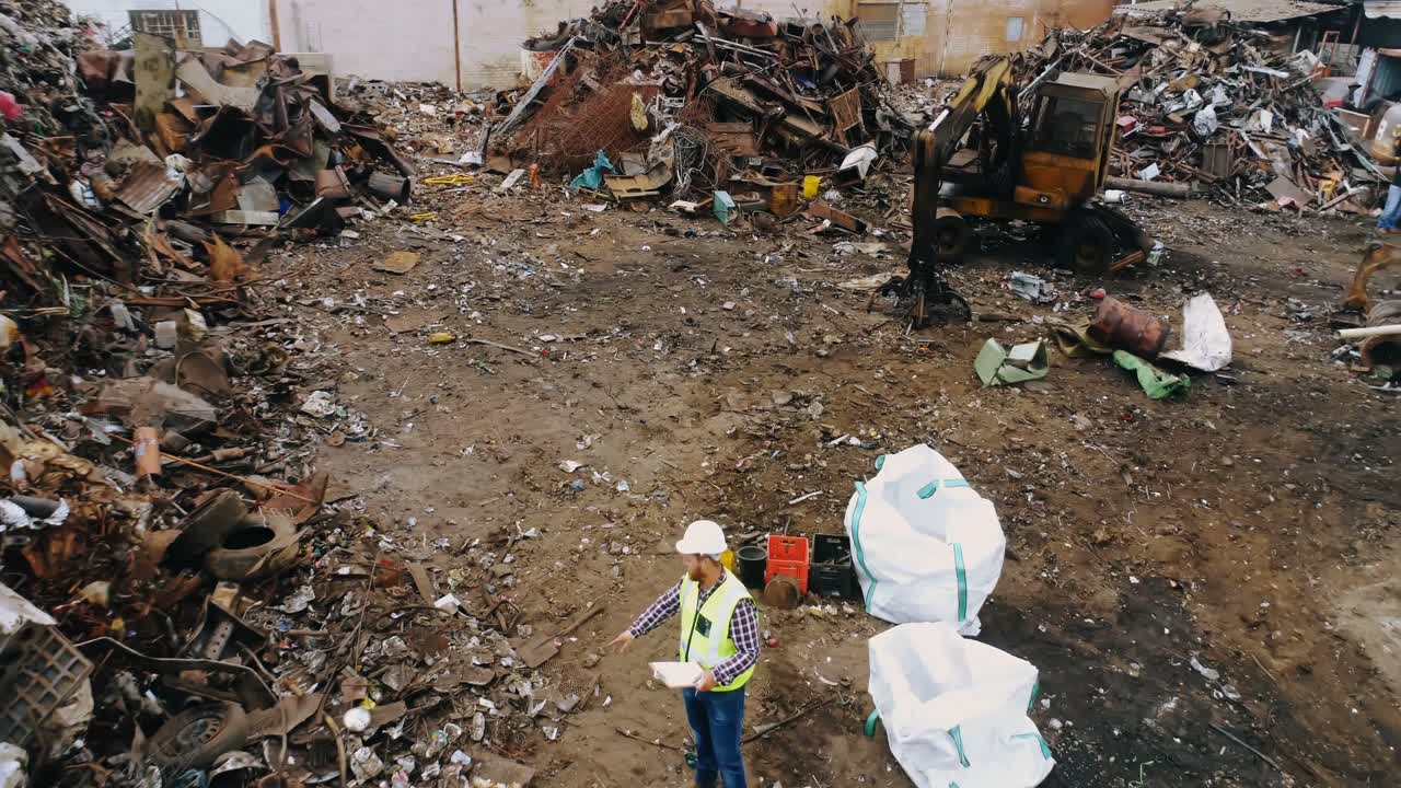 hombre chequeando chatarra en el depósito de chatarra 4k