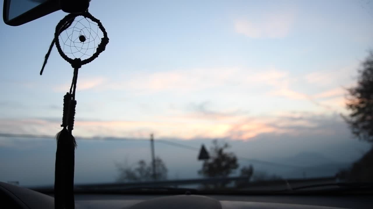 일몰 때 산길에서 차 안에서 움직이는 아름다운 수제 드림캐처