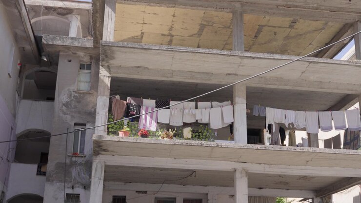 Edifício de concreto inacabado de vários andares com roupas penduradas no varal em uma varanda aberta