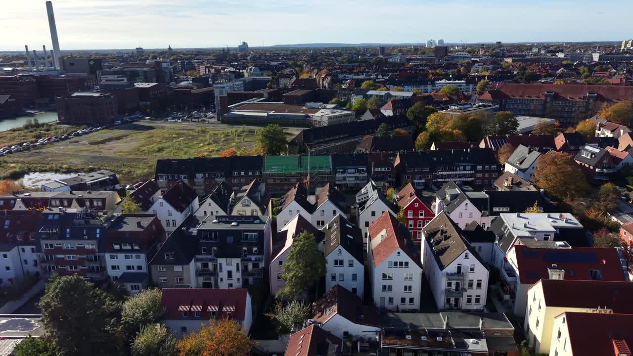 Row apartment houses in different style and color on sunny day in small German town. Aerial lateral wide shot. Colored trees in fall season. Tower in background. Münster, Germany, Europe